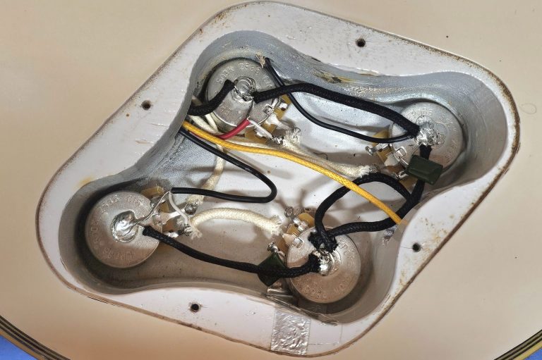 An acoustic guitar with a yellow cloth and a green electronic circuit board on it.